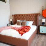 Elegant bedroom with tufted leather headboard and cozy decor in neutral tones.
