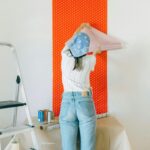 A woman applies polka dot wallpaper during a home makeover, showcasing DIY renovation.