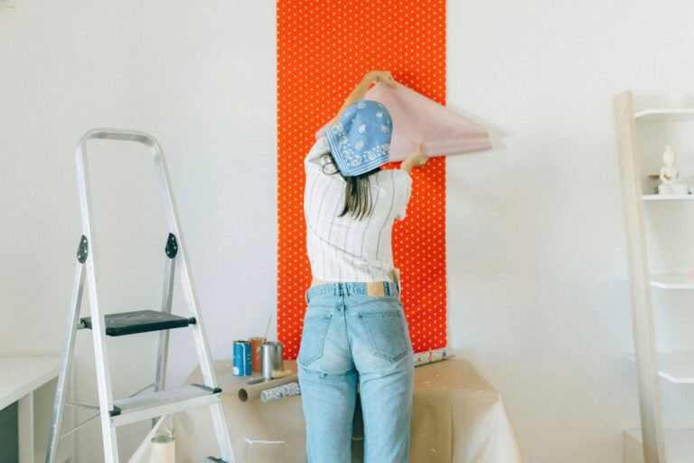 A woman applies polka dot wallpaper during a home makeover, showcasing DIY renovation.